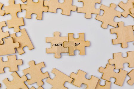 Diverse jigsaw puzzle pieces interlocking to form the word "STARTUP," symbolizing the teamwork