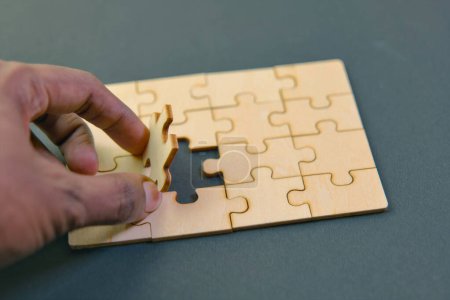 A hand holding the final piece to a jigsaw puzzle, symbolizing the critical role of finding a solution to complete a business challenge.