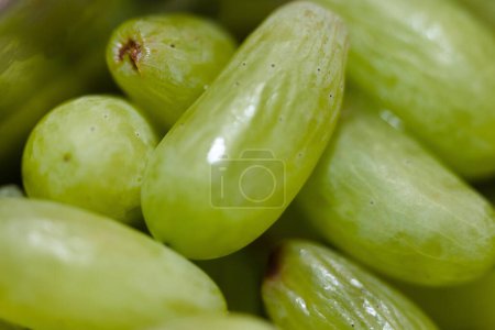 This close-up photo captures the intricate details of a bunch of ripe green grapes. Each grape is plump and glistening