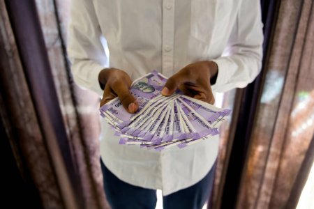 Dieses Bild handelt von Menschenhänden, die 100-Rupien-Scheine in der Hand halten