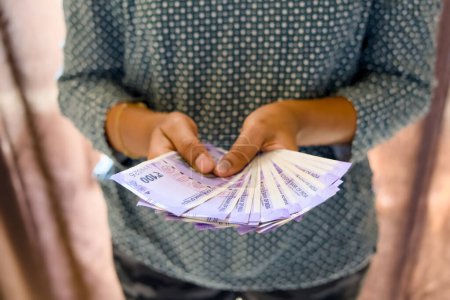 Ein Nahaufnahme-Foto der Hände einer Frau, die akribisch Stapel von Papiergeld zählt. Selektive Fokussierung unterstreicht die Rechnungen