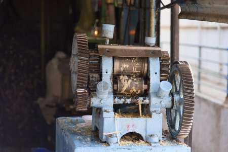 Téléchargez les photos : Une scène vibrante d'un vendeur en bord de route utilisant une machine à jus de canne à sucre en métal pour extraire le jus - en image libre de droit