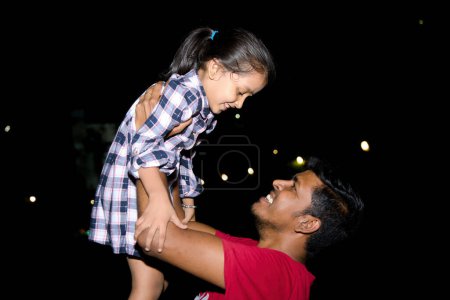 A heartwarming image of a father and his daughter laughing and playing together in a park