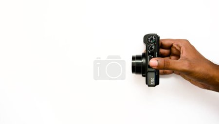 photo de stock représente une main saisissant un appareil photo numérique élégant, sur un fond blanc croustillant. La composition propre permet une intégration facile du texte ou des éléments de conception.