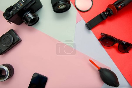 This image is about Flat lay photo of camera lens and accessories on colorful background