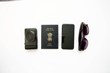 Une couche plate nette et nette mettant en valeur les articles de voyage essentiels passeport indien, appareil photo, lunettes de soleil et smartphone sur fond blanc.