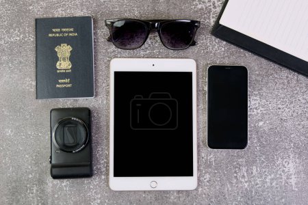 Dieses Archivfoto zeigt eine flache Anordnung von Reise-Must-haves, einschließlich Tablet, Reisepass, Sonnenbrille und Smartphone