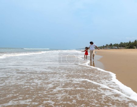 An mother and child share a heartwarming moment on a tranquil beach, pointing out to sea.