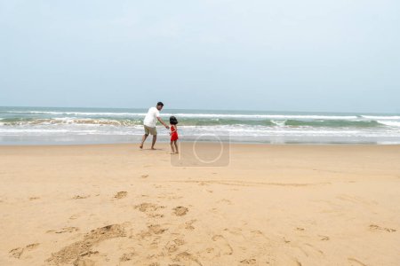 Une scène évocatrice se déroule alors qu'un père et un enfant se promènent le long d'une plage déserte, les mains jointes dans un moment de connexion.