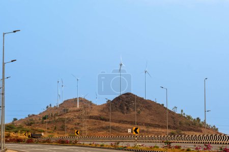 Téléchargez les photos : Serene highway scene with wind turbines atop a distant hill, symbolizing sustainable energy. - en image libre de droit
