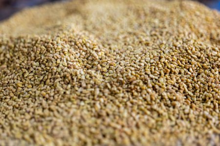 Eine Nahaufnahme von goldgelben Bockshornkleesamen auf einem lebendigen Gewürzmarkt, der kulinarische Traditionen und aromatische Köstlichkeiten hervorruft