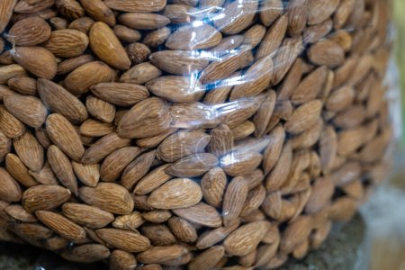 Close-up view of raw almonds in a transparent plastic bag, ideal for health-conscious themes. Fresh, natural, and organic.