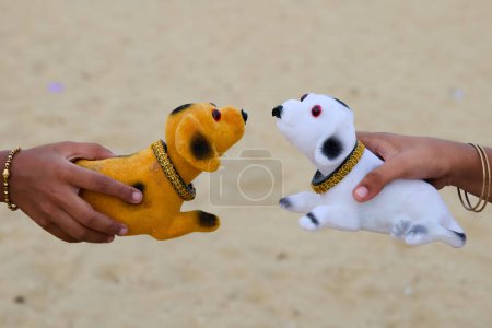Two hands hold plush dog toys, mimicking interaction. Golden retriever and Dalmatian toys meet playfully.