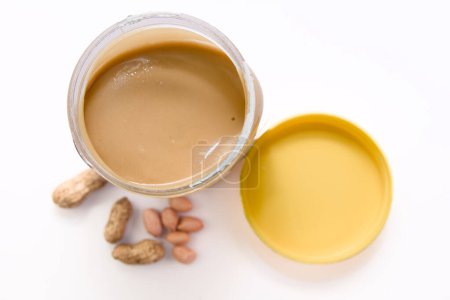 A close-up view of a glass jar overflowing with delicious, creamy peanut butter