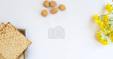 Téléchargez les photos : Matza dans une assiette en argent, avec des noix et des fleurs jaunes. Éléments de la Pâque pour une bénédiction et une carte de voeux. vue du dessus de matza, Pessah juive (Pessah) concept de vacances - en image libre de droit