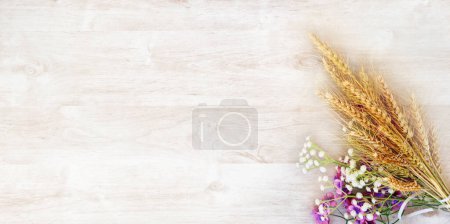 Foto de Ramo de trigo amarillo maduro con flores púrpuras y blancas, sobre una superficie de madera blanca. Destinado a una tarjeta de felicitación para las vacaciones de Shavuot - Imagen libre de derechos