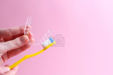 Téléchargez les photos : Nettoyage des aligneurs en plastique avec une brosse à dents. Photo de haute qualité - en image libre de droit
