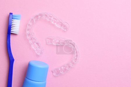 Téléchargez les photos : Aligneurs dentaires en plastique transparent et produits de soins sur un fond coloré. Photo de haute qualité - en image libre de droit