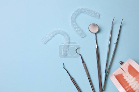 Téléchargez les photos : Aligneurs et outils en plastique transparent pour dentistes sur un fond coloré. Photo de haute qualité - en image libre de droit