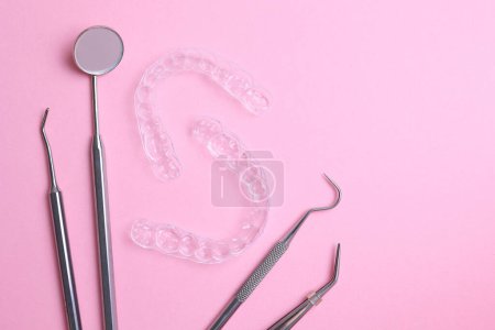 Transparente Kunststoff-Aligner und Zahnarztwerkzeuge auf farbigem Hintergrund. Hochwertiges Foto
