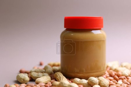 Téléchargez les photos : Beurre d'arachide et arachides crues sur un fond coloré. Photo de haute qualité - en image libre de droit