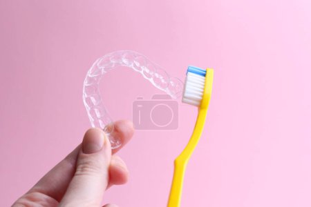 Téléchargez les photos : Nettoyage des aligneurs en plastique avec une brosse à dents. Photo de haute qualité - en image libre de droit