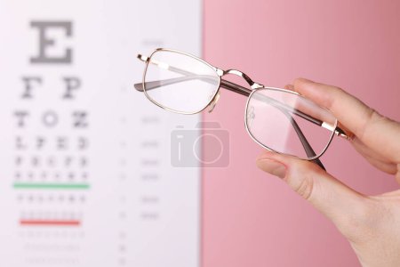 Foto de Gafas de corrección de visión en la mano sobre el fondo de una mesa de prueba de visión con espacio para el texto. Foto de alta calidad - Imagen libre de derechos