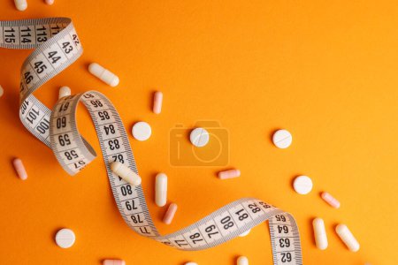 Photo for Centimeter tape and pills on a colored background with space for text. concept of losing weight, diet, fat burning, healthy eating. minimalism. . High quality photo - Royalty Free Image