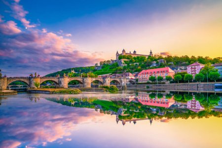 La fortaleza de Marienberg y el viejo puente principal se reflejan en el río en la colorida puesta de sol. Wurzburg, Baviera, Alemania