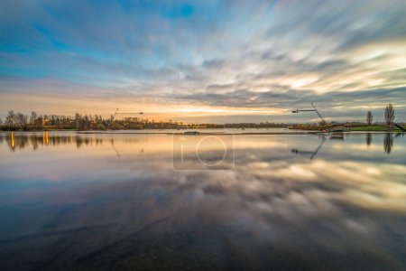 Téléchargez les photos : Lever de soleil au lac Willen à Milton Keynes, Angleterre. Longue exposition avec ciel trouble - en image libre de droit
