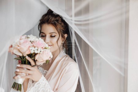 Photo for Wedding interior. The bride's dressing at the hotel. Wedding photography. Portrait of a cute bride. bride brunette sniffs a bouquet - Royalty Free Image