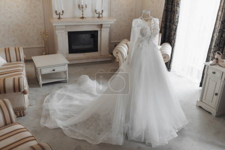 elegante vestido de novia con un tren largo en un maniquí se encuentra en una habitación de hotel con un interior real
