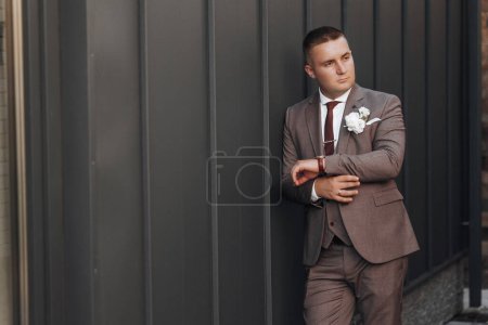 Photo for Portrait of an adult male groom in a stylish suit of brown shades outdoors. - Royalty Free Image