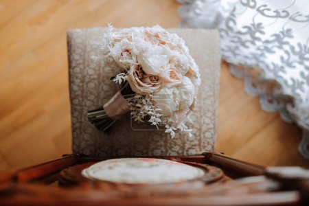 Téléchargez les photos : Style maison. Bouquet de mariage de fleurs crème et rose sur une chaise à la maison sous la lumière du jour. Détails de la mariée et du marié. - en image libre de droit