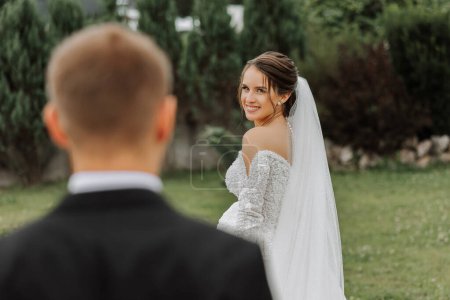 Photo for The bride is dressed in an elegant lush white wedding dress with a long veil and is ready for her groom. The first meeting of the bride and groom - Royalty Free Image