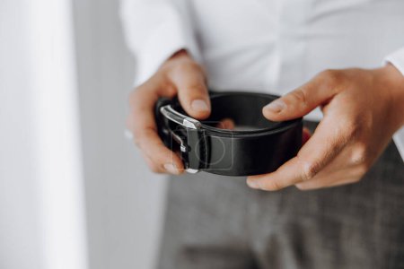 Photo for A man is holding a black belt in his hand. The belt is made of leather and is black in color - Royalty Free Image