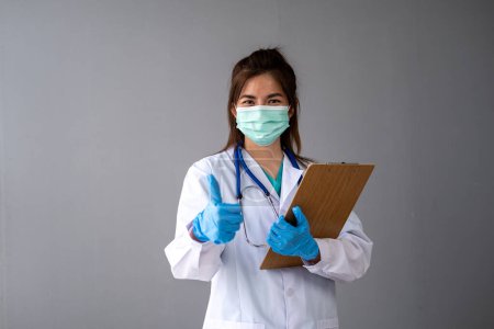 Foto de Enfermera doctora con máscara que se pone guantes médicos, doctora con uniforme blanco que usa máscara y guantes de goma - Imagen libre de derechos