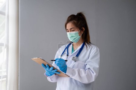Photo for Female nurse doctor with a mask putting on medical gloves, woman doctor in white uniform wearing mask and rubber gloves - Royalty Free Image