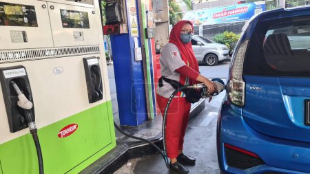 Foto de Personal ayudando a llenar combustible subsidiado de Pertalite en un coche azul. - Imagen libre de derechos