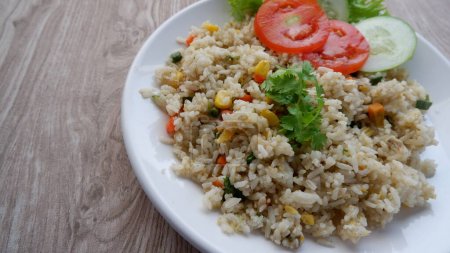 Téléchargez les photos : Légumes indonésiens riz frit (nasi goreng) avec oeuf, pois mange-tout, tranche de laitue de concombre et de tomate. - en image libre de droit