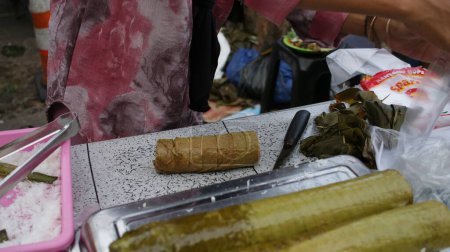 Foto de Alimento tradicional de Iftar: arroz glutinoso Lamang Tapai con leche de coco y envoltura de hojas de pandan en hoja de plátano y asado dentro de bambú joven. Gastronomía especial de Minangkabau. - Imagen libre de derechos