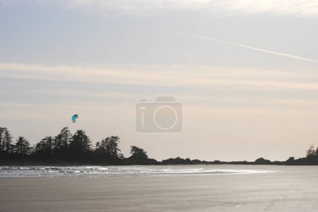 Téléchargez les photos : Un cerf-volant surfe sur les vagues avec des îles derrière lui près de Tofino, BC, Canada - en image libre de droit