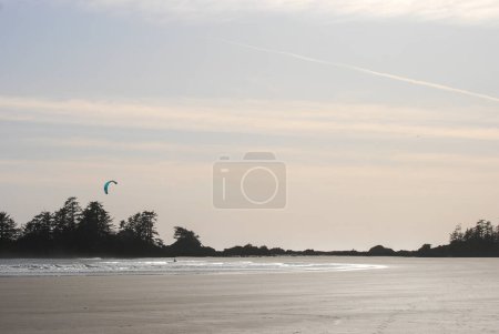 Téléchargez les photos : Un cerf-volant surfe sur les vagues avec des îles derrière lui près de Tofino, BC, Canada - en image libre de droit