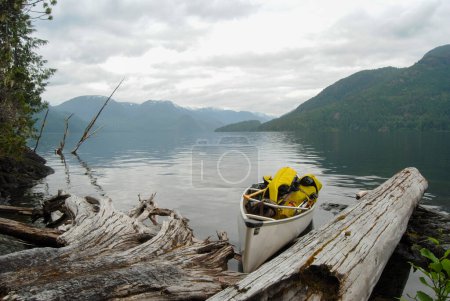 Téléchargez les photos : Un canot d'expédition se trouve au bord d'un calme Grand lac Central, île de Vancouver, C.-B., Canada - en image libre de droit