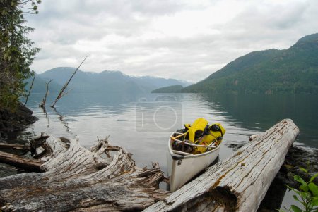 Photo for An expedition canoe sits at the shore of a calm Great Central Lake, Vancouver Island, BC, Canada - Royalty Free Image