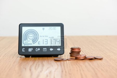 Téléchargez les photos : Smart meter and coins to represent cost of fuel and electricity for household bills - en image libre de droit
