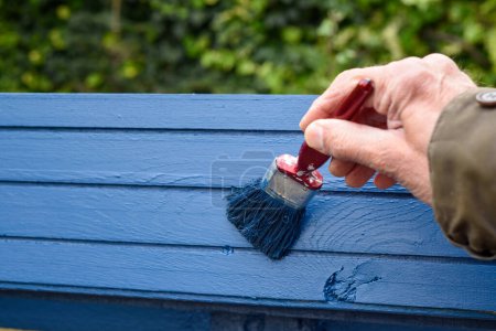 Main masculine utilisant un pinceau pour peindre sur une planche de bois
