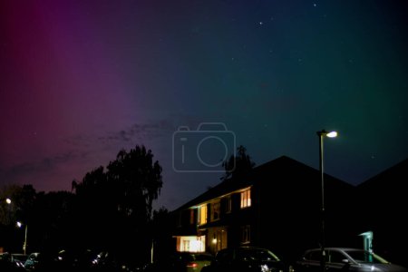 Northern lights or Aurora Borealis provide colourful lights in the night sky over a residential street during a solar storm in space
