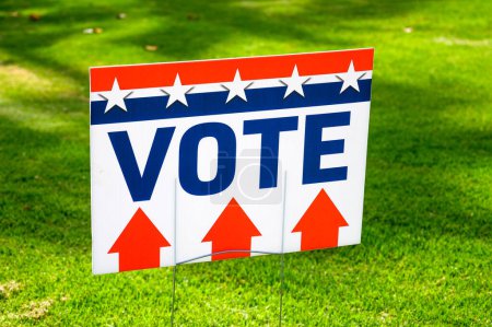 Téléchargez les photos : Une pancarte VOTE dans un bureau de scrutin sur de l'herbe verte. Photo de haute qualité - en image libre de droit