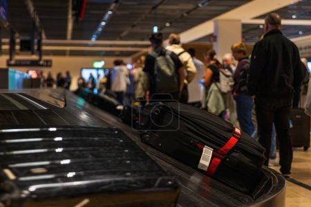 Foto de Personas que esperan su maleta en la cinta transportadora de equipaje en la reclamación de equipaje en el aeropuerto - Imagen libre de derechos